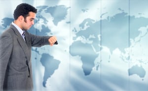 Business man looking at the time with a world map in the background