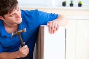 Young man building furniture using a hammer and a nail at home